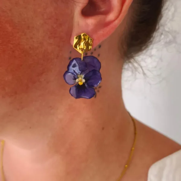 Boucle d’oreille pensée violette naturelle avec support doré texturé, portée à l’oreille – bijou végétal raffiné et élégant