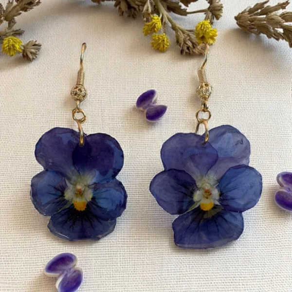 Boucles d’oreilles en résine avec fleurs de pensée bleutée, montées sur crochet doré – bijou floral délicat fait main