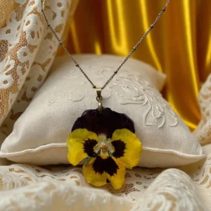 Collier avec pensée séchée jaune-brune montée en pendentif doré, porté autour du cou – bijou naturel L’Atelier d’Emy‑Lys