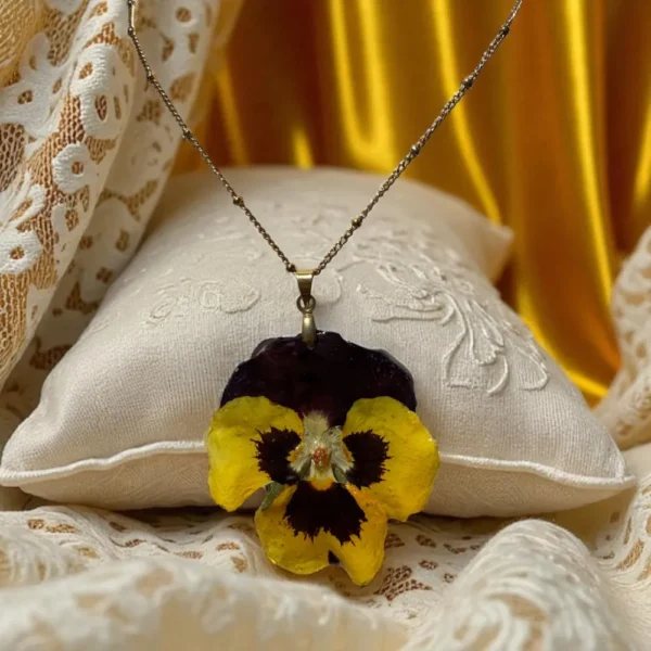 Collier avec pensée séchée jaune-brune montée en pendentif doré, porté autour du cou – bijou naturel L’Atelier d’Emy‑Lys