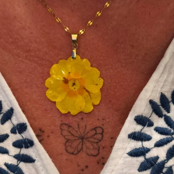 Collier doré orné d'une primevère jaune éclatante, bijou floral fait main porté au creux du cou, création unique de L’Atelier d’Emy-Lys.
