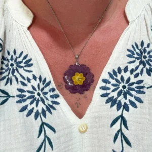 Pendentif en forme de fleur de primevère violette et jaune, monté sur chaîne argentée et porté sur décolleté, bijou naturel fait main par L’Atelier d’Emy-Lys.