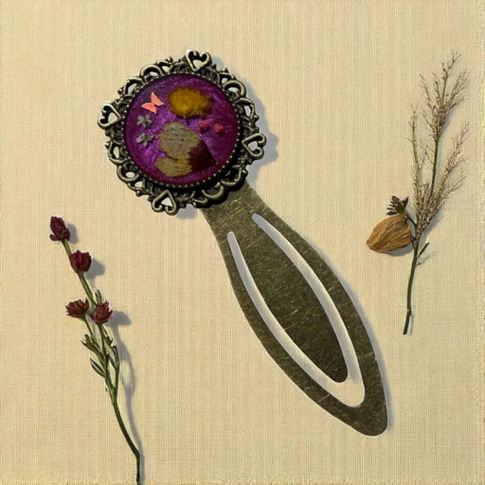 Marque-page en laiton au décor romantique, avec inclusion de fleurs séchées de mimosa et coreopsis dans un cabochon rond violet – création artisanale de L’Atelier d’Emy-Lys