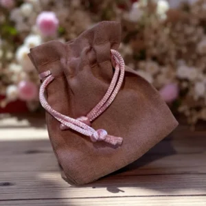 Pochette cadeau en tissu marron avec cordon rose, idéale pour protéger et offrir les bijoux artisanaux de L’Atelier d’Emy Lys