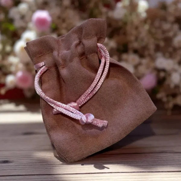 Pochette cadeau en tissu marron avec cordon rose, idéale pour protéger et offrir les bijoux artisanaux de L’Atelier d’Emy Lys