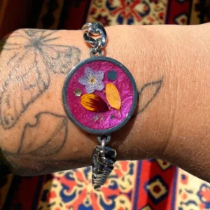 Bracelet artisanal argenté à maillons larges avec fleurs séchées de myosotis, pétale de ficaire et coreopsis dans un cabochon fuchsia irisé