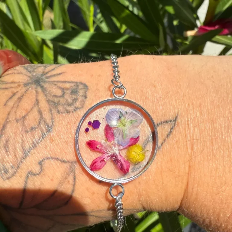 Bracelet argenté avec attache coulissante, cabochon rond en résine et fleurs séchées de véronique sauvage, mimosa et pétales de cassis, création florale faite main